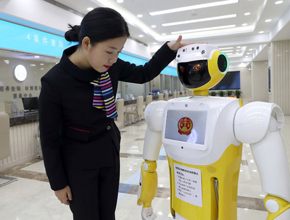 A staff member interacts with Xiaofa, a robot that provides simple legal advice and guidance for litigants, at Beijing No 1 Intermediate People's Court on Thursday. Zou Hong/China Daily