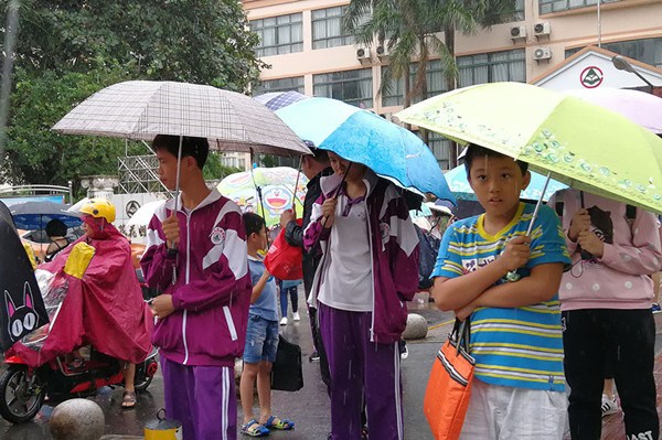Students are released at Changmao Garden School in Haikou, Hainan province, on Sunday. Schools in 10 cities and counties in Hainan will take a day off on Monday as Typhoon Khanun approaches. (Huang Yiming/China Daily)