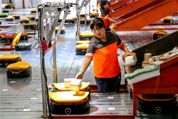 An employee of Shentong Express, a delivery company, uses robots to scan, weigh and sort mail automatically. More than 700 robots work at the company's sorting center in Yiwu, Zhejiang province. Photo/Xinhua