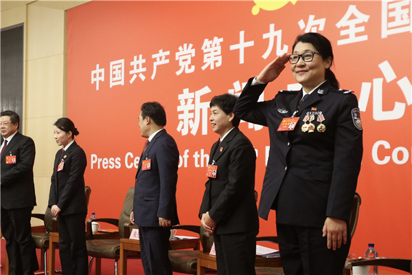 Tian Xuemei, a delegate to the 19th National Congress of the Communist Party of China, salutes journalists after a group interview session on Thursday. Tian serves as a forensic expert in the Ministry of Public Security. (Photo by Feng Yongbin/China Daily)