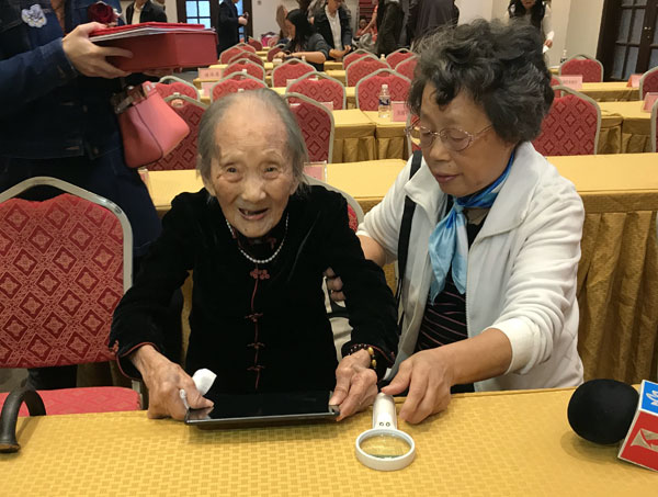 Wu Zhicheng (L), one of the 10 oldest women in Shanghai. The 107-year-old said she loves to eat meat, drink yellow wine and plays tablet computer and WeChat. (Photos by He Qi / chinadaily.com.cn)
