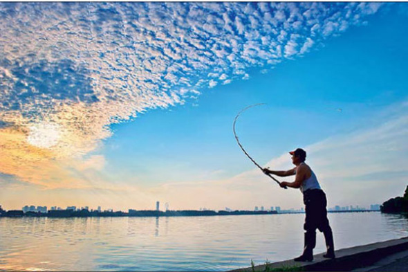 A fisherman casts off at Lihu Lake, Wuxi, in the early morning. (Photo by Rong Yiqing / For China Daily)