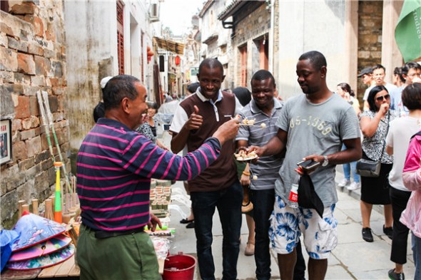 Nigerian Tochukwu Innocent Okeke (right) shopping for souvenirs in Wuyuan, Jiangxi province. (Photo by Lan Jian/For China Daily)