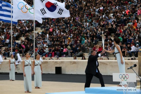Greek actress Katerina Lehou (1st R) in the role of an Ancient Greek High Priestess passes the Sacred Olympic Flame to Hellenic Olympic Committee President Spyros Capralos at Panathenaic stadium in Athens on Oct. 31, 2017, during the handover ceremony of the Olympic flame for the 2018 Winter Olympics in Pyeongchang, South Korea.(Xinhua/Marios Lolos)