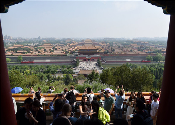 Tourists look at the Palace Museum at the Jingshan Park. (Photo/Xinhua)
