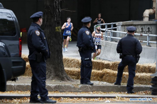 Policemen stand guard as runners participate in the New York City Marathon in Manhattan of New York, the United States, on Nov. 5, 2017. The New York City Marathon was held Sunday with heavy police presence as the massive event through the city was just days after a terrorist attack in Manhattan that killed eight people. (Xinhua/Li Muzi)