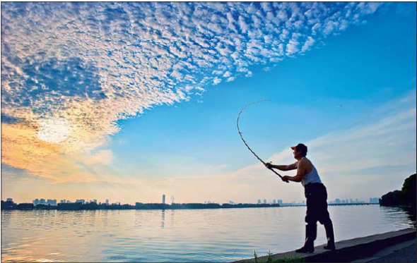A fisherman casts off at Lihu Lake, Wuxi, in the early morning. (Rong Yiqing / For China Daily)