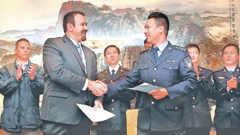 A representative of the International Cooperation Department of the Ministry of Public Security (right) hands the memorandum of understanding to a representative of the United States Department of Justice in Shanghai on Oct. 16, 2017. FAN JUN/XINHUA