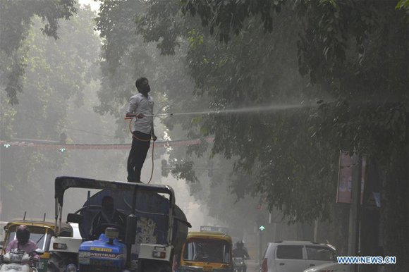 A municipal worker sprays water on the tree to settle dust as a measure against ongoing heavy pollution in the air in New Delhi, India on Nov. 9, 2017.(Xinhua/Sarkar)