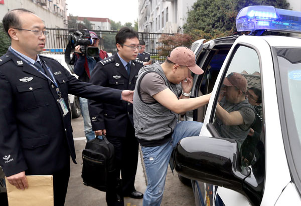 A fugitive suspected of theft from the United States is escorted to a police vehicle from a detention facility in Shanghai on Tuesday. He was later handed over to U.S. law enforcement officials. (Photo/Xinhua)