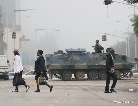 People walk past an armored vehicle on a street in Harare, capital of Zimbabwe, Nov. 15, 2017.   (Xinhua/Philimon Bulawayo)