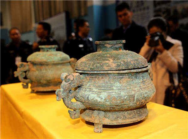 People examine relics on Tuesday that were recovered in a special operation in Xi'an, Shaanxi province. PhotoChina Daily/Huo Yan