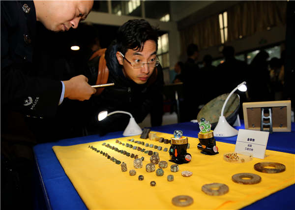 People examine relics on Tuesday that were recovered in a special operation in Xi'an, Shaanxi province. ��Photo��China Daily/Huo Yan��