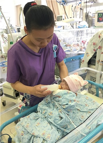 A nurse feeds a newborn baby at Children's Hospital of Fudan University in Shanghai earlier this month. (Provided to China Daily)