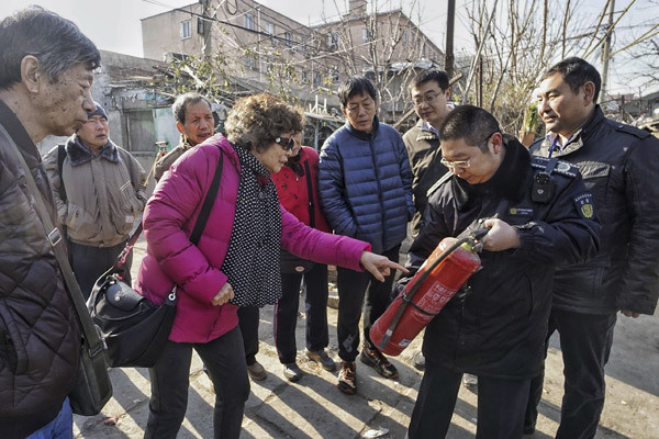 Security officials in Beijing's Fengtai district show residents how to put out fires on Monday during a safety push following a fatal weekend fire. (Photo/Xinhua)