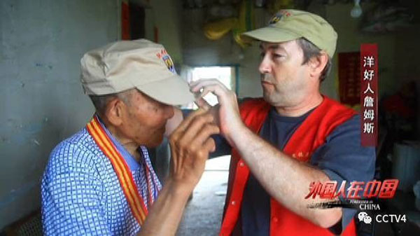 James helps adjust a veteran's hat. (Photo/screeshot of CCTV)