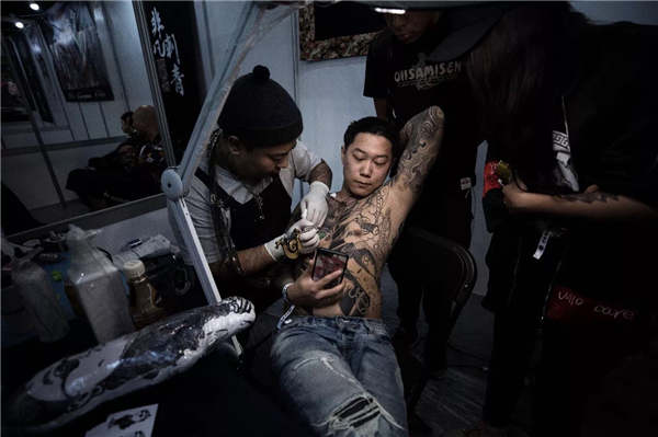 A tattooist inks a design on a customer during the China International Tattoo Convention in Ningbo in October. (Photo provided to China Daily)