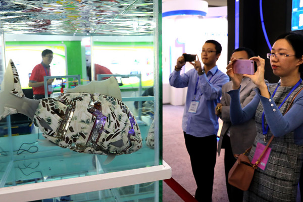 Visitors take photographs of an underwater robot in a tank at the China High-tech Fair 2017 held in Shenzhen, Guangdong province, on Nov 16, 2017. Xuan Hui / Provided to China Daily