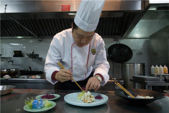 Wu Xinhua works on the final touch of a dish at Dan Cha Fan restaurant in Wuzhen. The helmsman of the popular eatery creates dishes with inspiration from different styles of cuisine. [Photo by Gao Erqiang/China Daily]