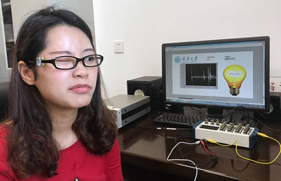 A test subject controls a virtual light bulb by blinking while wearing a pair of special eyeglasses with a new kind of microsensor.[Photo by Fu Xiaozhu/For China Daily]