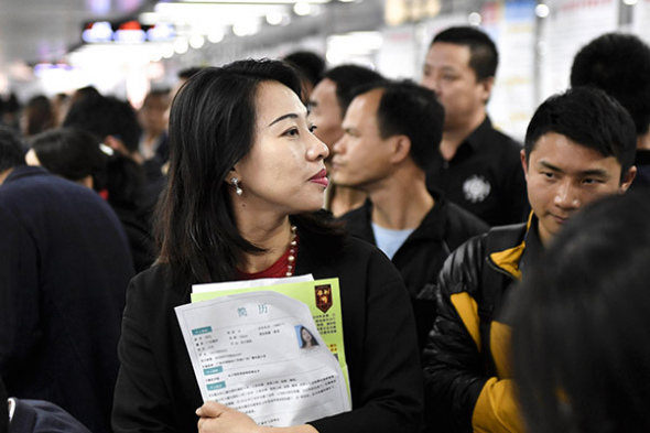 A job seeker looks through employment information at a job fair in Guangzhou in February. [Photo by Chen Jimin/China News Service]
