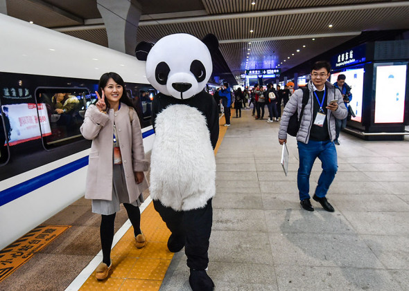 A passenger poses for a photo with a performer in a panda costume at Chengdu East Railway Station in Sichuan province on Wednesday. The Xi'an-Chengdu high-speed railway opened on Wednesday. Lyu Jia / For China Daily