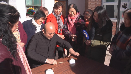 Village's CPC Secretary Wang Zhuhong plays a walnuts trick. /CGTN Photo