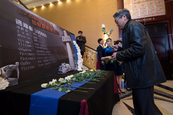 A man leaves a flower at the Commemorative Day Ceremony for the 80th anniversary of the Nanjing Massacre held on Saturday in Toronto. (Zou Zheng/China Daily)