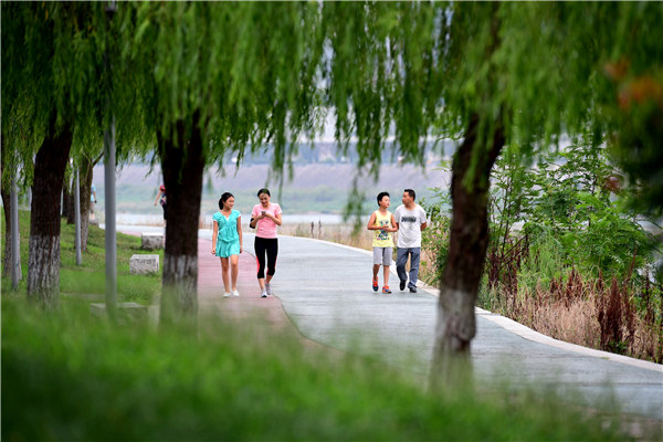 People stroll on a walking path near an embankment of Hanjiang River in Ankang, Shaanxi province. (Shao Rui/Xinhua)