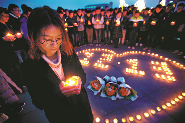 Students from Dongnan University in Nanjing light candles on Tuesday to commemorate the Nanjing Massacre, which began 80 years ago on Wednesday. A memorial hall commemorating the tribunal of accused war criminals in Tokyo will be built in Shanghai. (YANG BO / CHINA NEWS SERVICE)