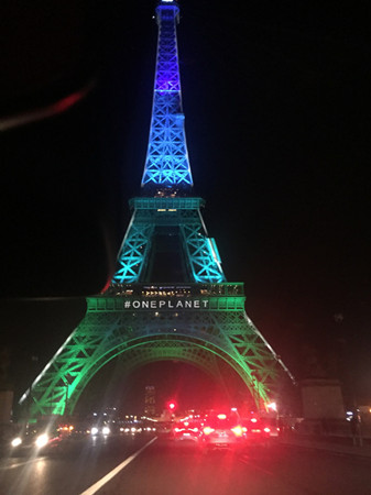Eiffel Tower is lit up with environmentally friendly colors on Tuesday night as One Planet Summit is held in Paris. (Fu Jing / China Daily)