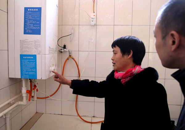 Qi Si'nyu, a villager in Hebei, shows off her new gas-fired boiler. (Photo by WANG JING/CHINA DAILY)