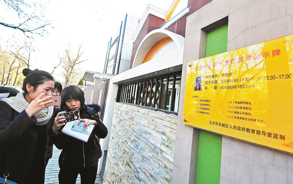 People take photos of the information board of an educational inspector outside a kindergarten in Beijing earlier this month. (Photo by YUAN YI/FOR CHINA DAILY)