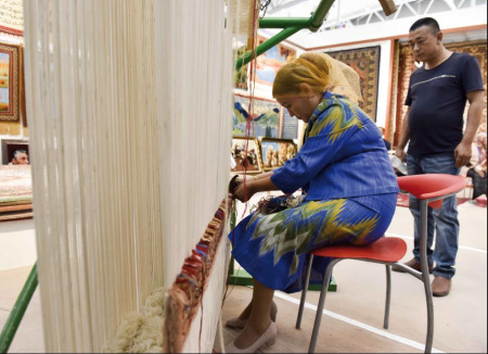 A craftsperson displays traditional Hotan carpet weaving at an exhibition held in Urumqi, the Xinjiang Uygur autonomous region. Photo Provided to China Daily.
