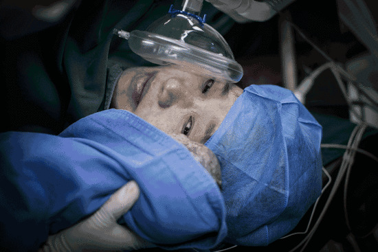 Fang Zhiying, a 48-year-old woman who lost her 24-year-old firefighter son in a blast in Tianjin in 2015, looks at her newborn infant at Zhongnan Hospital in Wuhan, Hubei province, on Thursday. JIADAI TENGFEI/FOR CHINA DAILY