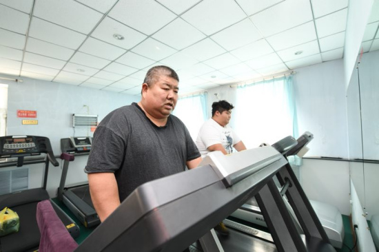 Tian Shiguang (L), 53, and his son Tian Hua, 29, exercise at a weight-losing hospital in Changchun. [Photo provided to chinadaily.com.cn]
