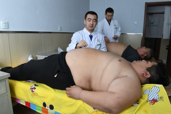 Tian Shiguang, 53, and his son Tian Hua, 29, receive treatment at a weight-losing hospital in Changchun. [Photo provided to chinadaily.com.cn]