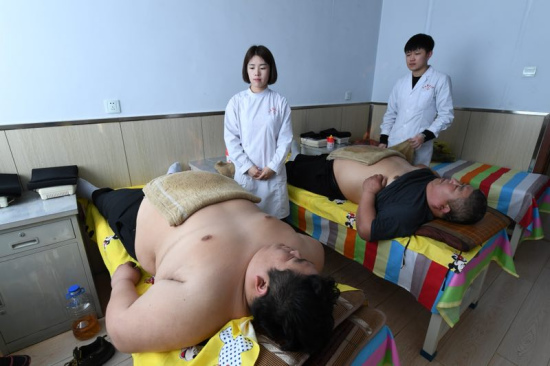 Tian Shiguang, 53, and his son Tian Hua, 29, receive treatment at a weight-losing hospital in Changchun. [Photo provided to chinadaily.com.cn]