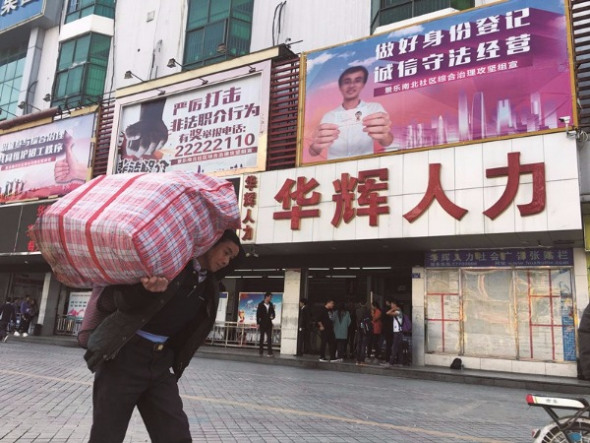 Migrant workers gather in front of one of the many labor recruitment agencies in Sanhe marketplace in Longhua, Shenzhen, Guangdong province. (Photo: China Daily/Roy Liu)