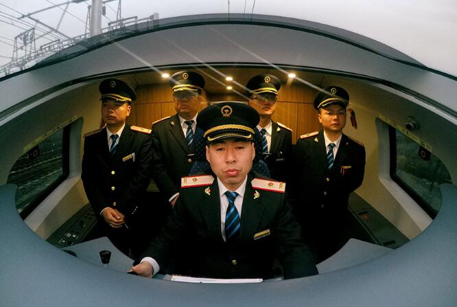 Wang Chuangcu (front) demonstrates how to drive a CRH 3A bullet train to new drivers. (Photo by Liu Xiang/China Daily)