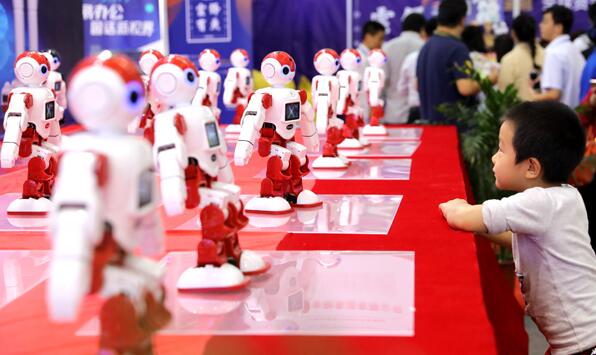 A boy watches robots in action at the 20th China International (Shenzhen) Hi-tech Fair in Shenzhen, Guangdong province, last month. (Photo by Xuan Hui/For China Daily)