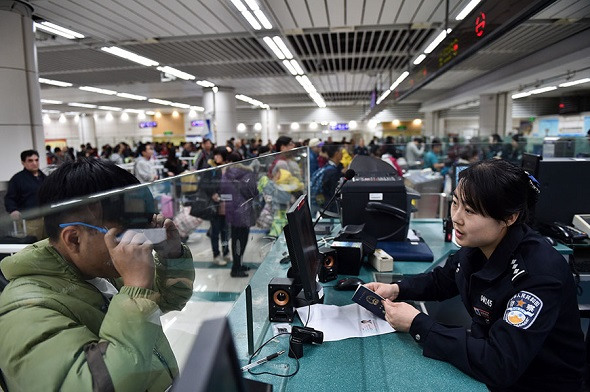 A border inspection police officer checks the identity of a traveler from Hong Kong in February last year at Shenzhen Bay Port. The port is a pilot for the joint checkpoint mechanism between Hong Kong and the mainland that was approved by the top legislature on Wednesday. (Photo/Xinhua)