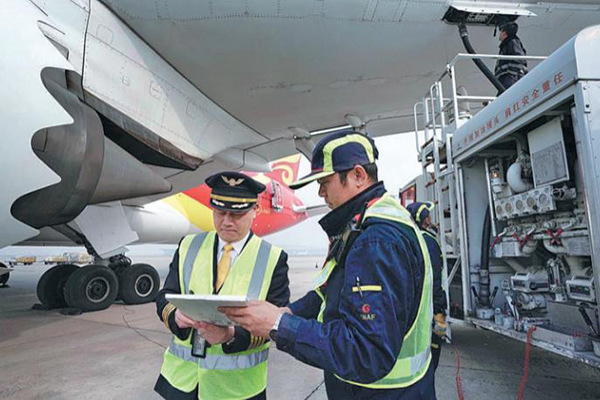 Sun Jianfeng (left), president of Hainan Airlines who is also a crew member of China's first bio-fuel international flight, checks the airplane's condition report at the Beijing Capital International Airport before departure for Chicago on Nov 21. (Photo provided to China Daily)