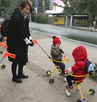 Two children ride yellow shared strollers as a woman watches them in Liyuan Square in Wuhan, Hubei province, on Sunday. Provided to CHINA DAILY