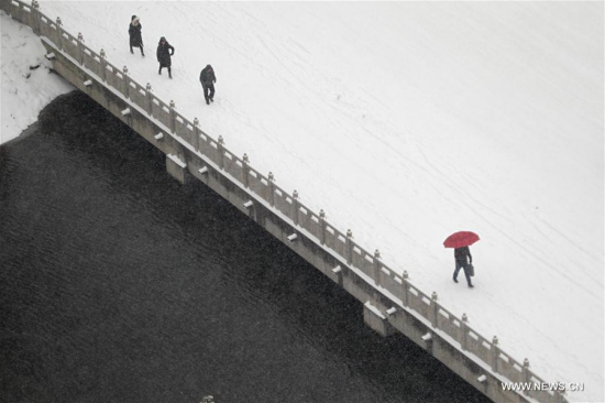 Pedestrians walk on a snow-covered bridge in Xuchang, central China's Henan Province, Jan. 4, 2018. Many places across China saw snowfall from Wednesday. (Xinhua/Niu Shupei)