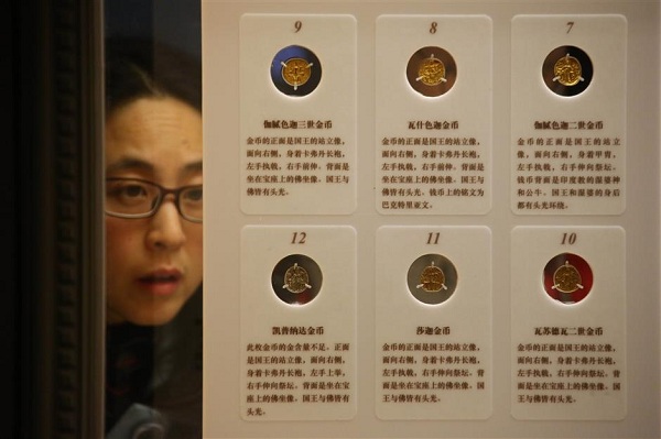 A visitor looks attentively at the different Kushan coins on display at the Shanghai Museum. (Wang Rongjiang/SHINE)