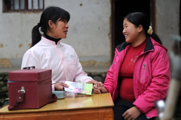 A family planning officer explains a healthcare pamphlet to a pregnant woman in Zhengang, Jiangxi. Photo/Xinhua