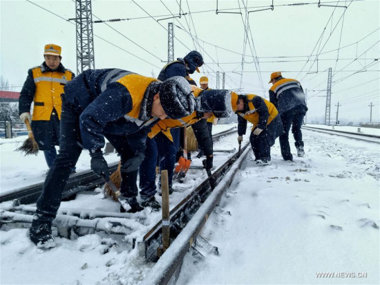 Staff members of the Zhengzhou Railway Group clear off snow and deice in Luoyang City, central China's Henan Province, Jan. 6, 2018. (Xinhua/Liang Xinfeng)