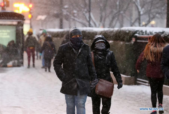 People walk in the snowfall in downtown Chicago, the United States, Dec. 29, 2017. (Xinhua/Wang Ping)