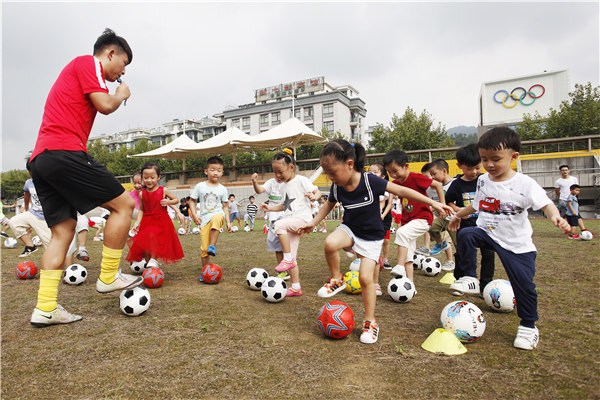 Kindergarten kids in Tonglu county, Zhejiang province enjoy their first soccer lesson under the guidance of a professional coach in September. (Xu Junyong/For China Daily)
